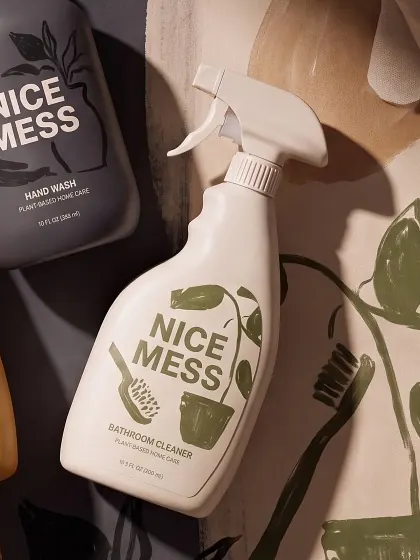 Bathroom Cleaner spray lying on a cream painted backdrop with olive leaves